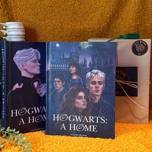 May include: Two hardcover books titled "Hogwarts: A Home" with character illustrations. The book covers feature portraits of young people in dark clothing. A package tied with twine and a green tassel is to the right.