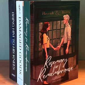 Puede incluir: Una pila de libros con varios títulos y diseños de portada. El libro principal presenta a una pareja tomados de la mano con el título "Rosemary for Remembrance". Otros títulos incluyen "Bring Him to His Knees" y "Damaged Goods".