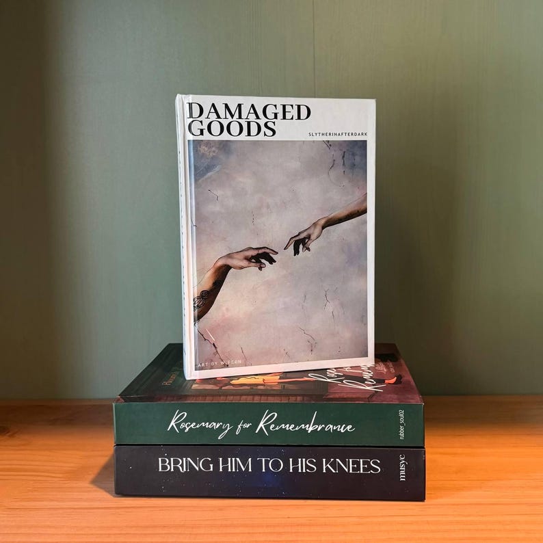 May include: A stack of three books with different covers. The top book is titled "DAMAGED GOODS" with an image of two hands reaching out. Below it is a book with "Rosemary for Remembrance" and the bottom book reads "BRING HIM TO HIS KNEES".