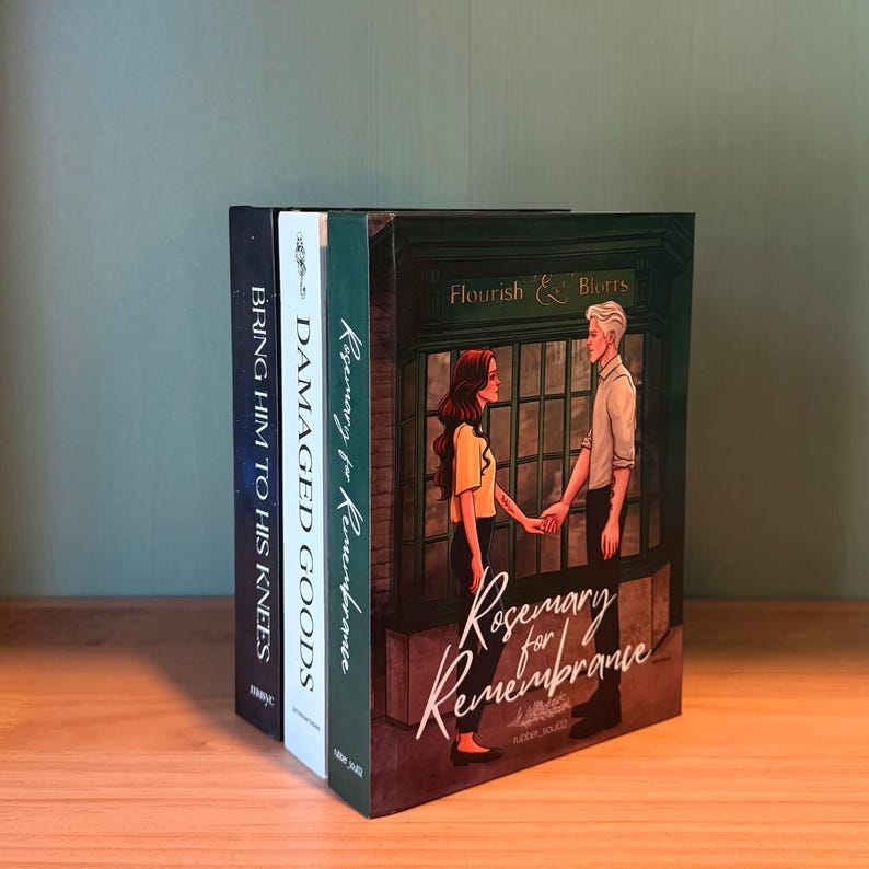 May include: A stack of books with various titles and cover designs. The front book features a couple holding hands with the title "Rosemary for Remembrance." Other titles include "Bring Him to His Knees" and "Damaged Goods."