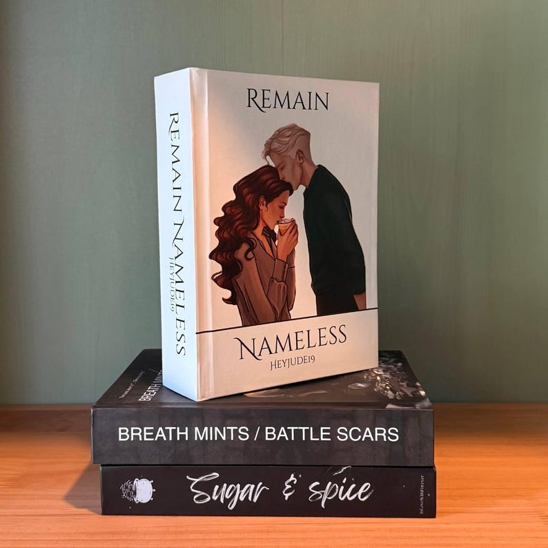 May include: A stack of three books. The top book is titled "Remain Nameless" with an illustration of a couple. The spine reads "Remain Nameless Heyjude19". Below it is a book titled "Breath Mints / Battle Scars". The bottom book is titled "Sugar & Spice".
