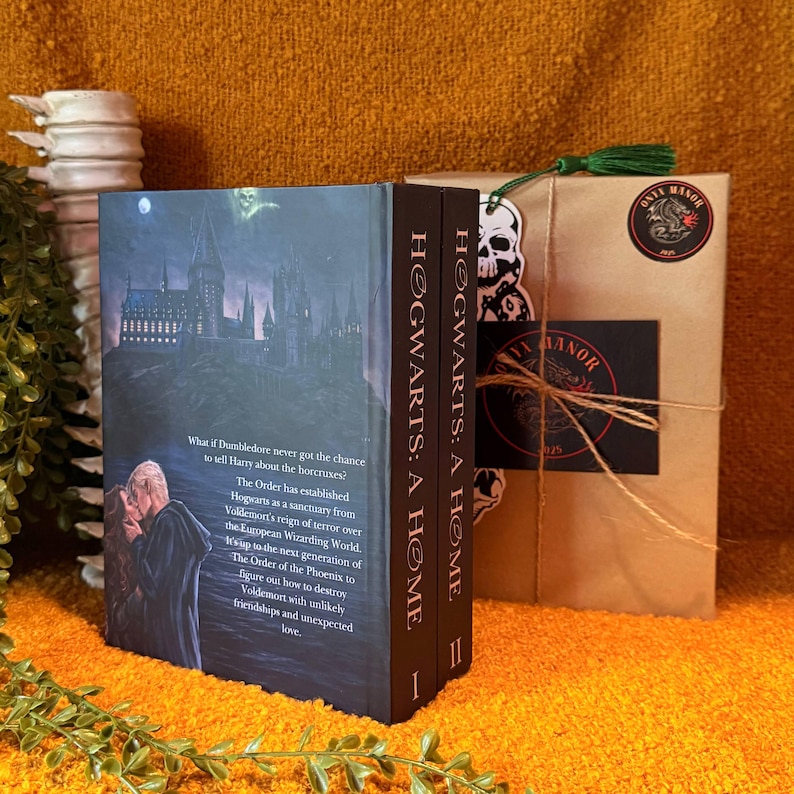 May include: Two hardcover books titled "Hogwarts: A Home" with a dark cover featuring a castle and a couple. A wrapped package with a skull sticker and a green tassel is next to the books. The package has a sticker that says "ONTE MANOR".