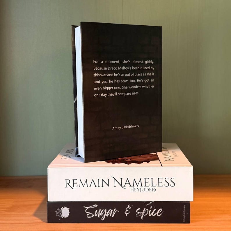 May include: A stack of three books with white and black covers. The top book is black with white text, the middle book is white with black text that reads "REMAIN NAMELESS", and the bottom book is black with white text that reads "Sugar & spice".