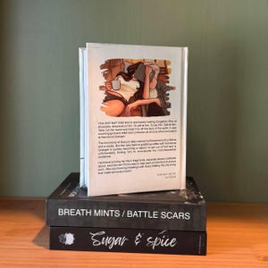 May include: A stack of three books with a white book on top featuring an illustration of two people with a coffee cup and a book. The middle book is black with the title "BREATH MINTS / BATTLE SCARS". The bottom book is black with the title "Sugar & spice".
