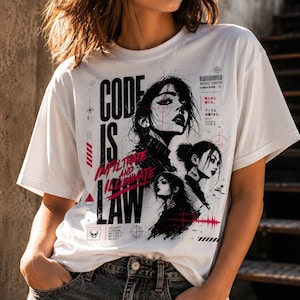Könnte beinhalten: Ein weißes Kurzarm-T-Shirt mit einem schwarzen und magentafarbenen Grafikdruck. Das Design zeigt drei stilisierte Porträts von Personen, den Text "CODE IS LAW", "INFILTRATE AND ILLUMINATE", "REBEL YOUTH" sowie verschiedene technische Symbole.