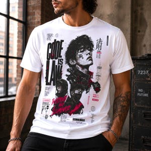 Puede incluir: Una camiseta blanca de manga corta con un estampado gráfico que incluye el texto "CODE IS LAW" e "INFILTRATE AND ILLUMINATE". El diseño presenta retratos estilizados, caracteres japoneses, elementos de código de barras y detalles en rojo y negro.