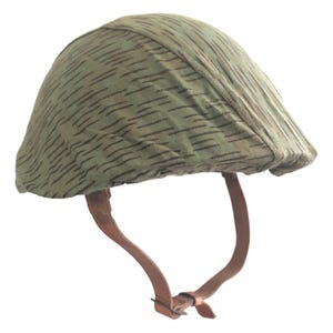 Puede incluir: Un casco militar vintage con un patrón de camuflaje de rayas verdes y marrones. El casco tiene una forma redondeada y está equipado con una correa de barbilla de cuero marrón. El diseño sugiere un artículo histórico o de colección.