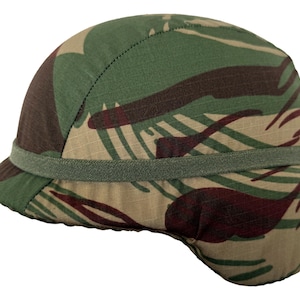 May include: A camouflage helmet in green, brown, and beige. The helmet has a rounded shape with a small brim and a band around the middle. The fabric has a textured appearance, and the pattern is similar to military camouflage.