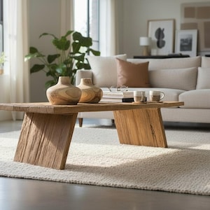K&ouml;nnte beinhalten: Rustikaler Couchtisch aus Holz mit schr&auml;gen Beinen. Auf dem Tisch stehen zwei Holzvasen und zwei Tassen. Der Tisch steht auf einem cremefarbenen Teppich in einem Wohnzimmer. Nat&uuml;rliches Design.