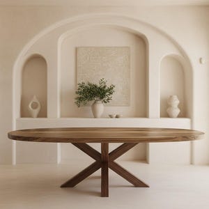 May include: An oval dining table with a natural wood grain top and a dark brown wooden base featuring four intersecting legs that form an X-shape. The table is positioned in a room with arched wall niches containing decorative vases and greenery.