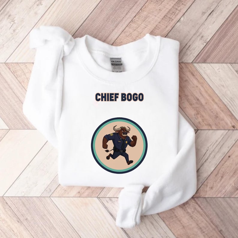 May include: White sweatshirt with the text "CHIEF BOGO" above a circular graphic. The graphic features a cartoon bull in a police uniform running. The bull is brown with a blue uniform and a badge.