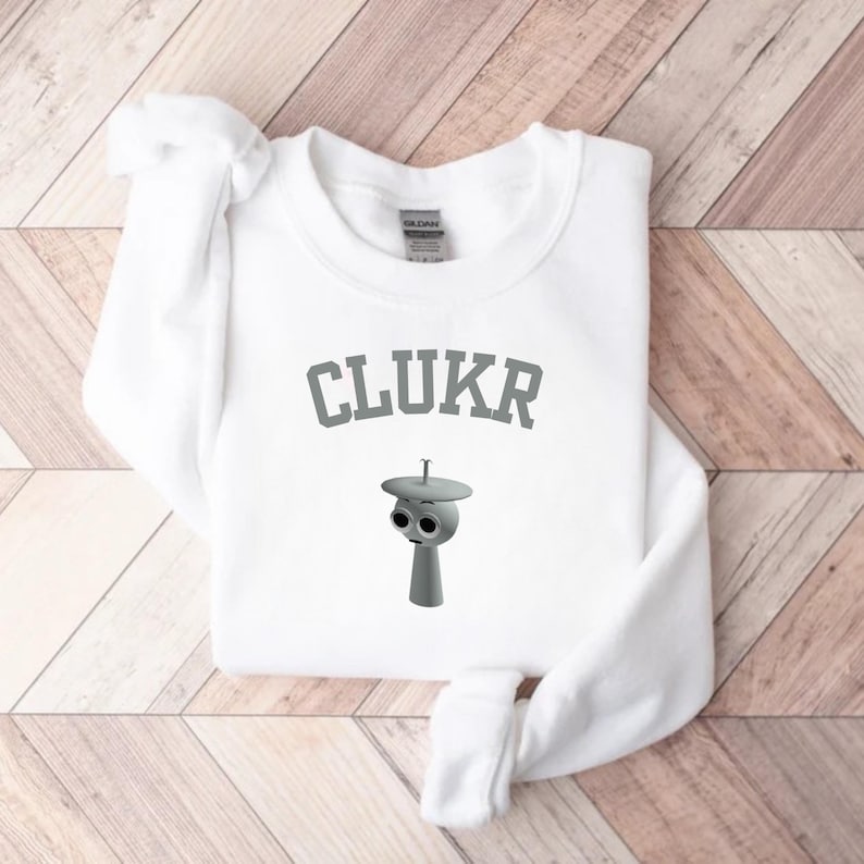 May include: A white ceramic mug with a black handle and the text "But First, Coffee" in a bold, black font. The mug is set against a blurred background, suggesting a cozy setting. The mug appears to be approximately 4 inches tall.