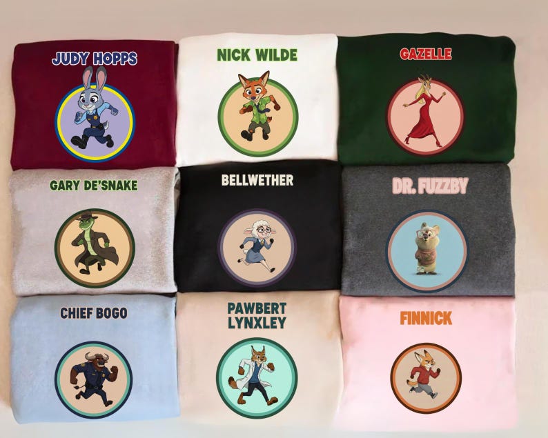 May include: A collection of nine sweatshirts in various colors, each featuring a circular graphic of a character from the animated film "Zootopia." The sweatshirts display character names like "Judy Hopps," "Nick Wilde," and "Gazelle."