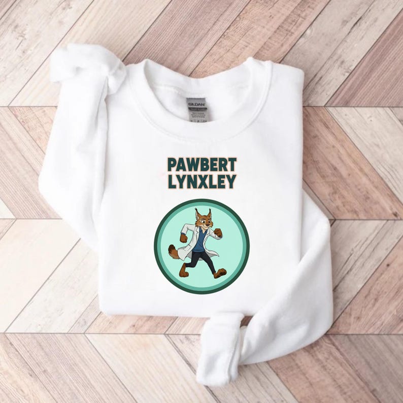 May include: White sweatshirt with the text "PAWBERT LYNXLEY" above a cartoon lynx character wearing a lab coat and running inside a green circle. The sweatshirt is on a light wood grain surface.