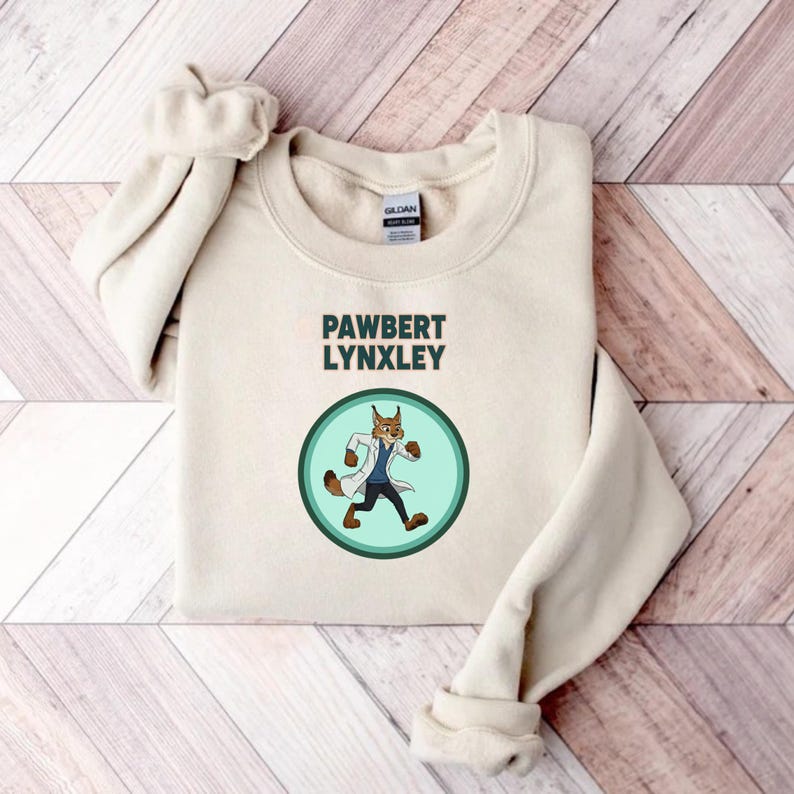 May include: Cream-colored sweatshirt with the text "PAWBERT LYNXLEY" above a circular graphic. The graphic features a cartoon lynx wearing a lab coat and walking. The sweatshirt has long sleeves and a crew neck.