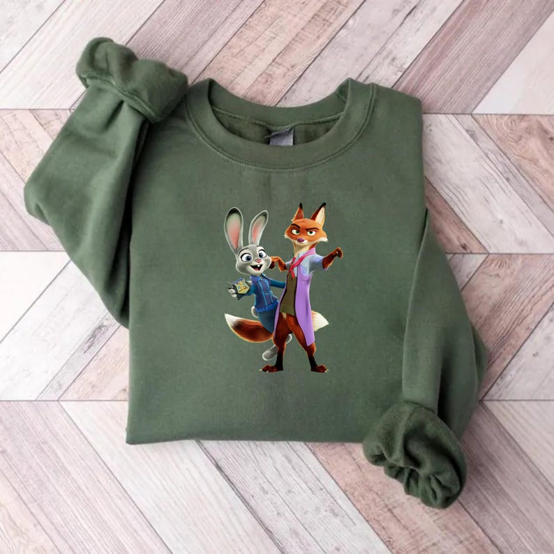May include: An olive green sweatshirt featuring a colorful graphic of two animated characters, a rabbit and a fox, in a friendly pose. The sweatshirt has long sleeves and a crew neck. The graphic is centered on the front of the shirt.