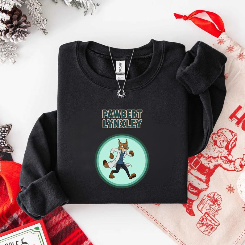 May include: Black crewneck sweatshirt featuring the text "PAWBERT LYNXLEY" above a cartoon lynx character in a lab coat. The lynx is inside a light green circle. A silver necklace is visible.