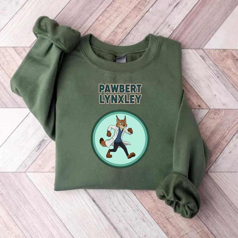 May include: An olive green sweatshirt featuring the text "PAWBERT LYNXLEY" above a circular graphic. The graphic depicts a cartoon lynx in a lab coat and blue shirt. The sweatshirt has long sleeves.