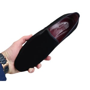 May include: Black velvet loafer with a rounded toe. The shoe has a burgundy interior and the brand name "Scarpetto" is visible inside. The shoe is held in a person's hand.