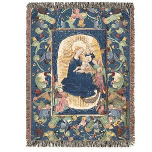 May include: A rectangular woven throw blanket featuring a central depiction of a figure holding a child surrounded by a golden halo against a dark blue background. The border displays intricate floral and vine patterns in muted tones with fringe.