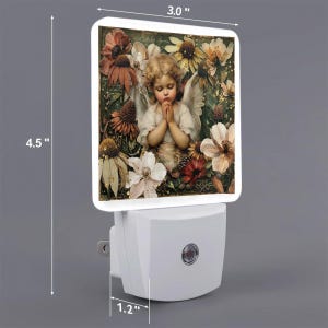 May include: A rectangular night light featuring a printed image of a young angel with wings praying amidst various brown, white, and yellow flowers. The device has a white plastic base with a circular switch and measures 3.0 inches by 4.5 inches.