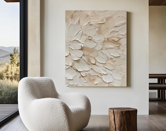 May include: A large abstract painting with a textured, layered design in shades of white and beige hangs on a neutral wall. A white, rounded, fluffy armchair sits in front of a large window. A small, natural wood stump serves as a side table.