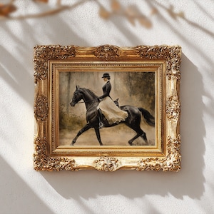May include: A framed painting depicting a rider in a black jacket and hat on a black horse, wearing a long cream-colored skirt. The artwork is encased in an ornate, rectangular gold frame with intricate relief carvings along the edges.