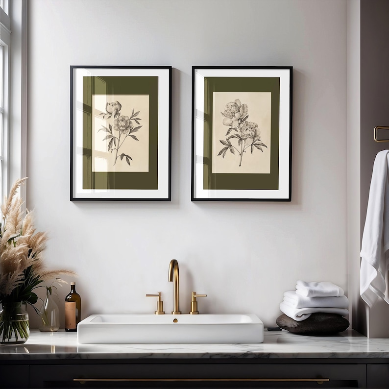 Set of two vintage botanical peony wall art prints in gold frames with green matting, styled above a farmhouse kitchen sink with brass fixtures and white hydrangeas in a soft blue cottage-style kitchen.