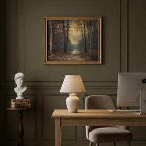 May include: A framed landscape painting depicting a forest path leading to a lake under a soft sky, displayed above a desk with a cream-colored ceramic table lamp, a white computer monitor, a gray chair, and a white bust on a small wooden table.
