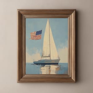 May include: A framed painting of a sailboat on the water under a blue sky. The sailboat has a white sail and an American flag. The frame is a light brown color.