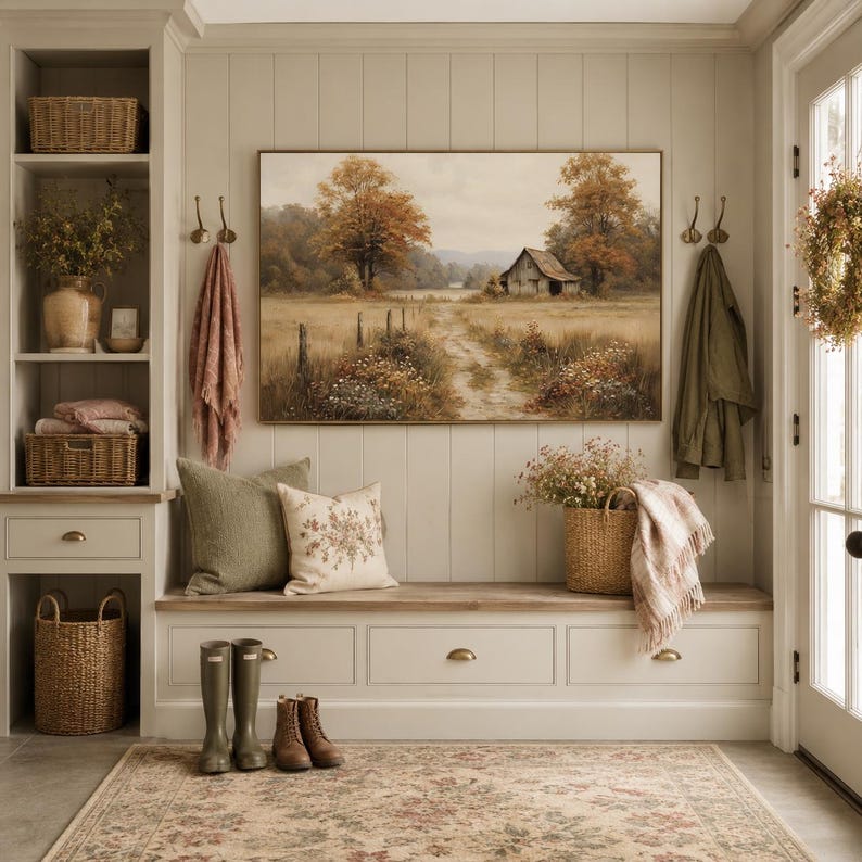 May include: A mudroom entryway featuring a built-in bench with drawers, a landscape painting of a barn in a field, two woven baskets, a floral patterned rug, olive green and cream throw pillows, a wicker basket with flowers, and rain boots.