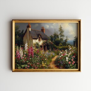Op de afbeelding: Een ingelijst schilderij van een huisje met een stenen dak, gelegen in een kleurrijke tuin. Een pad leidt naar de deur, omringd door roze, rode, witte en gele bloemen. Het kunstwerk is gepresenteerd in een goudkleurige lijst.