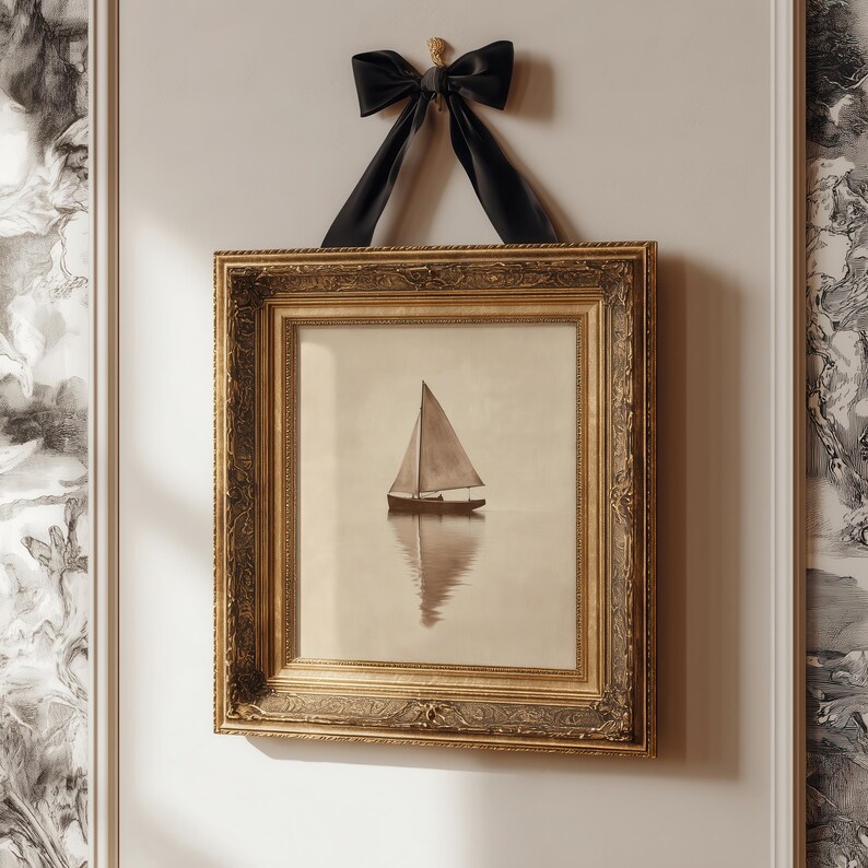 May include: A framed print of a sailboat on calm water, displayed with a gold ornate frame and a black velvet bow. The print has a sepia tone, and the frame is rectangular.