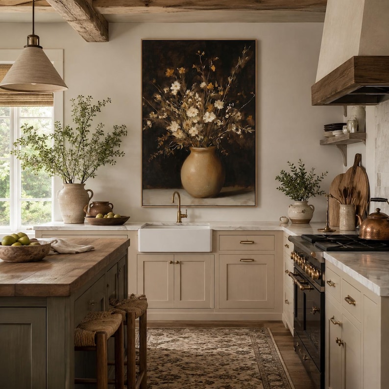 May include: A kitchen interior featuring a large framed painting of a floral bouquet in a tan vase above a white farmhouse sink. The space includes a wooden island, beige cabinetry, a black range, a copper kettle, and a patterned area rug.