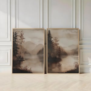 Op de afbeelding: Twee ingelijste verticale wandkunstprints met een sepia-landschap van een kalm meer omringd door dichte dennenbossen en verre bergen. Het kunstwerk toont een zachte, wazige sfeer met gedempte bruine en beige kleurenpaletten.