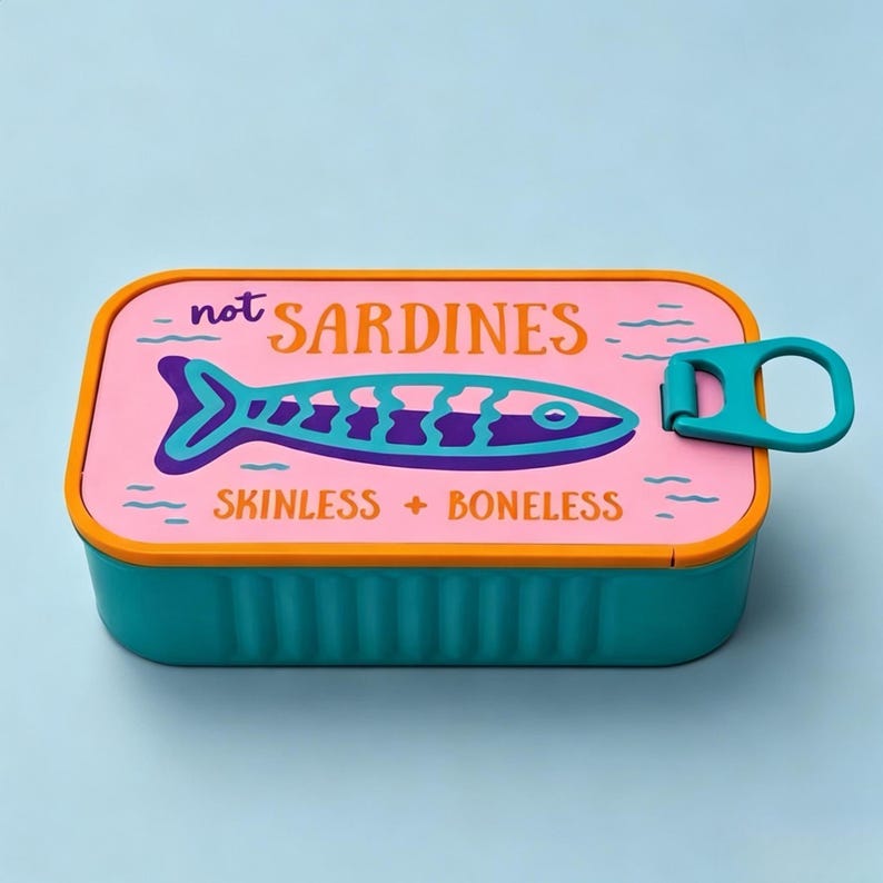 Puede incluir: Un recipiente de almacenamiento rectangular de color verde azulado con una tapa rosa y borde naranja. La tapa muestra un gr&aacute;fico de pez morado y azul con el texto "not SARDINES" y "SKINLESS + BONELESS" en naranja y morado, y una leng&uuml;eta.