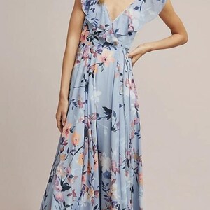 May include: A light blue floral print maxi dress with a V-neckline and ruffled trim. The dress features a flowing skirt and a delicate floral pattern in shades of pink, purple, and blue. The dress is floor-length.