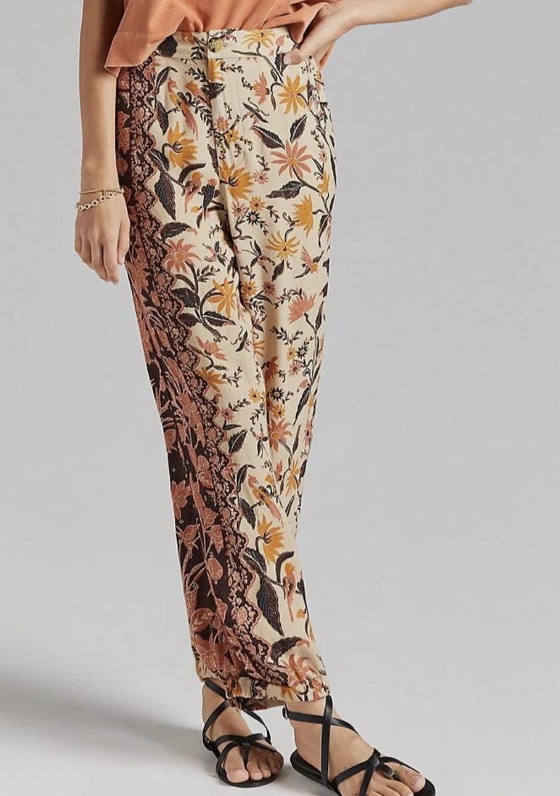 Puede incluir: Pantalones con estampado floral en beige, marr&oacute;n y naranja. Los pantalones presentan un patr&oacute;n floral detallado con un dise&ntilde;o de borde contrastante. Se combinan con sandalias negras. El estilo es bohemio y casual.