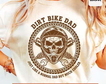 May include: Cream-colored t-shirt with a brown graphic. The graphic features a skull wearing a motorcycle helmet, crossed wrenches, and the text "DIRT BIKE DAD JUST LIKE A NORMAL DAD BUT MUCH COOLER." Below the graphic is the text "High Quality SVG + PNG."