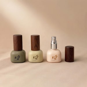 Peut inclure: Trois petits flacons décoratifs avec des bouchons en bois. L'un est vert olive, l'autre crème et le troisième rose clair. Chaque flacon porte un motif floral et le mot "Luck". Les bouchons en bois sont brun foncé.