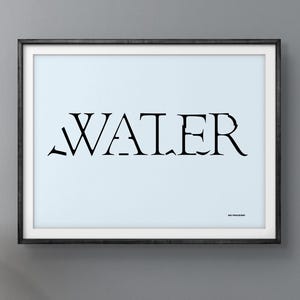 May include: A framed art print with the word "WATER" in black, stylized font on a light blue background. The print hangs above a wooden cabinet with black doors and a black lamp.