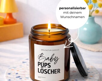 Könnte beinhalten: Ein brennendes braunes Glas-Kerzenglas mit schwarzem Deckel, das auf einem dekorativen Untersetzer steht. Die Kerze hat ein weißes Etikett mit dem Text "Baby Pups Löscher". Die Kerze ist 150 ml.