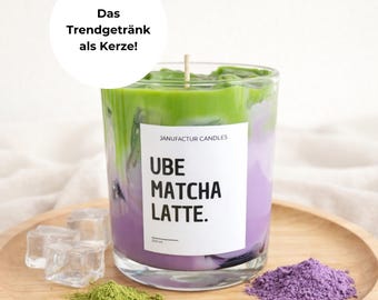 Könnte beinhalten: Eine Kerze in einem Glas mit geschichtetem Design, das einen Ube Matcha Latte nachahmt, mit grünem und lila Wachs. Die Kerze steht auf einem Holztablett mit Eiswürfeln, grünem Pulver und lila Pulver. Das Etikett lautet "UBE MATCHA LATTE."