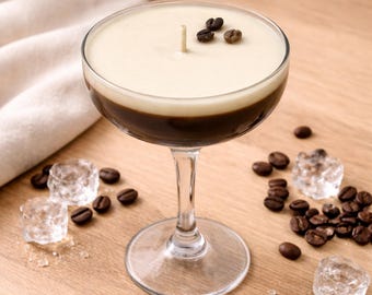 Könnte beinhalten: Eine Kerze in einem klaren Glas-Coupe-Glas mit einem zweischichtigen Design aus einem dunkelbraunen Boden und einer cremeweißen Oberseite. Ein einzelner Baumwolldocht ist mittig im Wachs platziert und mit drei Kaffeebohnen verziert.