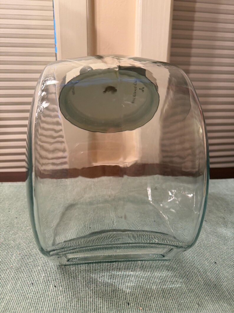 May include: A clear, rectangular glass container with rounded corners and a wide opening at the top. The vessel features a thick, transparent glass construction with a smooth surface and a slightly curved base, designed for storage or display purposes.