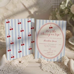 May include: Two baby shower invitations. One features a pattern of red cherries on a light blue striped background. The other has text inside a red oval that reads "He's the Cherry on top!" and details for Amelia Jane's baby shower.