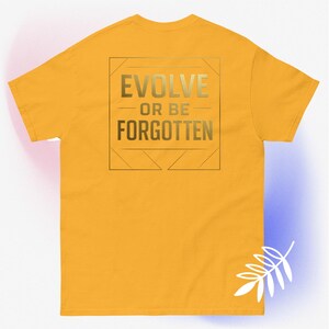 May include: Mustard yellow t-shirt with a gold graphic on the back. The graphic features the words "EVOLVE" above "OR BE" and "FORGOTTEN" in a square and triangle design.