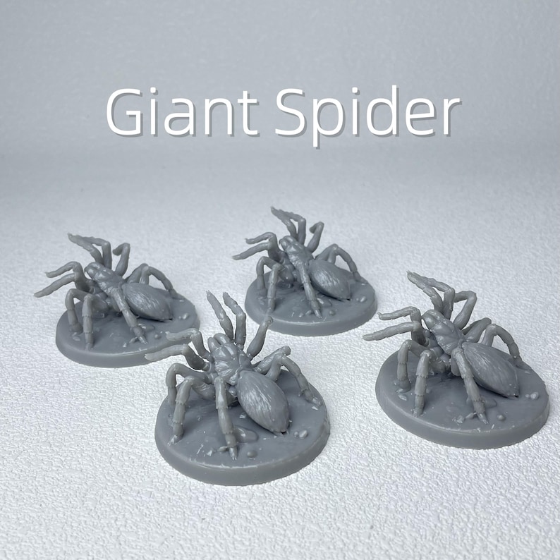 May include: Four gray miniature giant spider figurines. Each spider is on a circular base. The text "Giant Spider" is displayed in white above the figurines. The spiders have multiple legs and a detailed body.