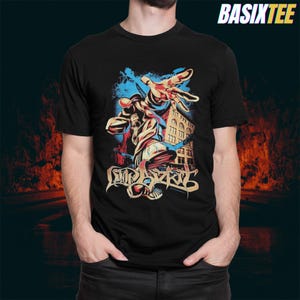 May include: Black t-shirt featuring a colorful graphic of a figure reaching out, with a cityscape backdrop. The design includes the text "EMPIREZ". The shirt has a crew neck and short sleeves. The brand name "BASIXTEE" is printed in white on the top right.