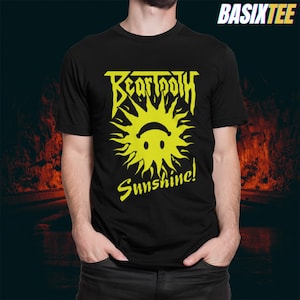 May include: Black t-shirt featuring a yellow graphic of a smiling sun with the word "BEARTOOTH" above and "Sunshine!" below. The shirt is made of a soft material.